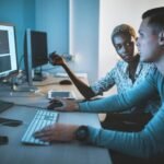 Deux développeurs web collaborant sur la création et l'optimisation d'un site internet, affichant du code sur un écran d'ordinateur dans un environnement professionnel.